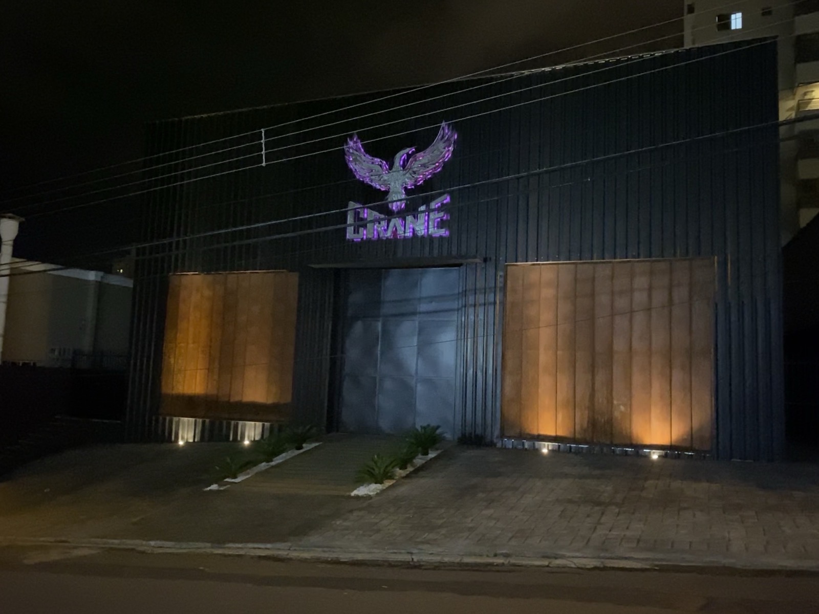 Fachada da Crane à noite, com a logo iluminada